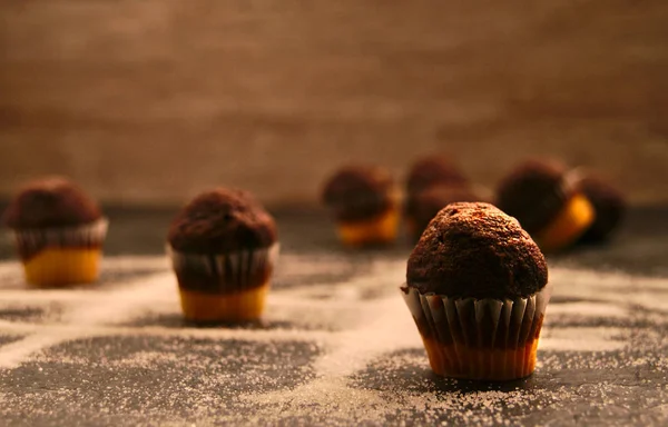 Üste üç resmini üzerinde düz küçük çikolata muffins kullanarak oyun, çizgiler olarak koyu yüzey üzerinde ahşap arka plan olarak şeker.