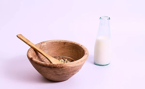 45 derece fotoğraf ahşap kase, müsli içinde ve yanındaki küçük süt şişesi