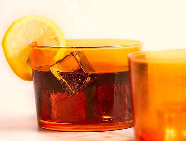 Soda, ICES ve bir dilim limon, portakal bir bardak ve bir turuncu cam önünde closeup
