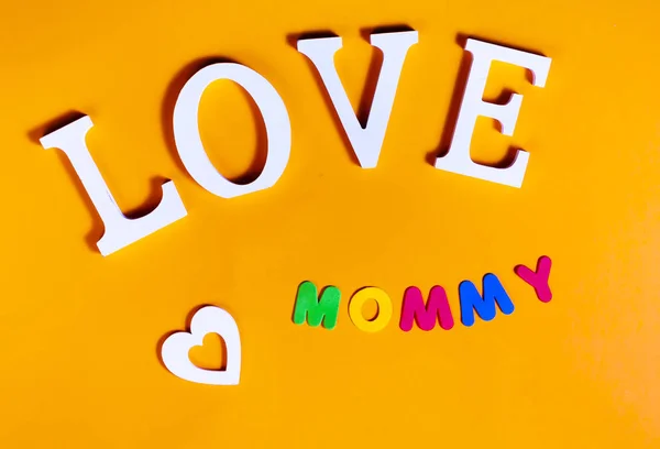 白の単語の愛 白心臓とオレンジ色の背景での文字色ママのオーバーヘッドの画像 — ストック写真