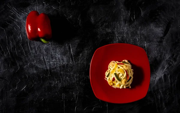 Pasta over red dish and red pepper