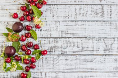 büyük tatlı sulu kiraz, Erik ve üzüm, yapraklar ve çiçekler ahşap arka plan, sağlıklı beslenme kavramı üzerinde