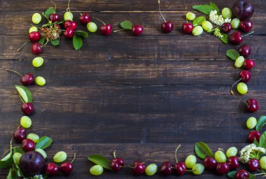 Olgun kiraz yaprakları, üzüm ve çiçek bir ahşap tahta üzerinde bir bahçeden bir çerçeve. Yukarıdan görüntülemek