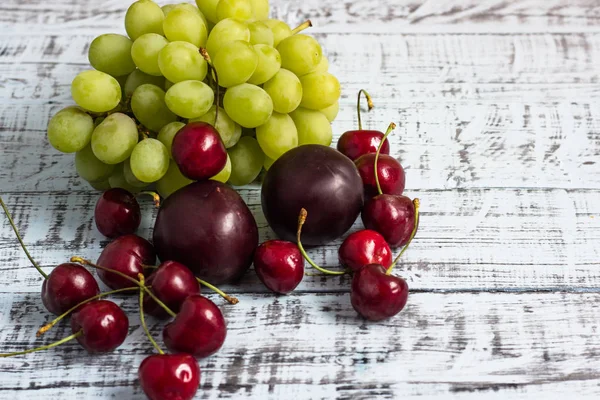 büyük tatlı sulu kiraz, Erik ve ahşap arka plan, sağlıklı beslenme kavramı üzerinde üzüm