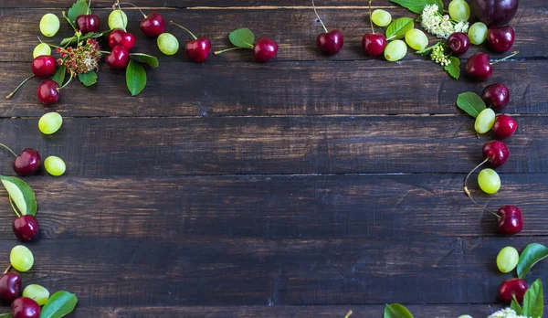 Olgun kiraz yaprakları, üzüm ve çiçek bir ahşap tahta üzerinde bir bahçeden bir çerçeve. Yukarıdan görüntülemek