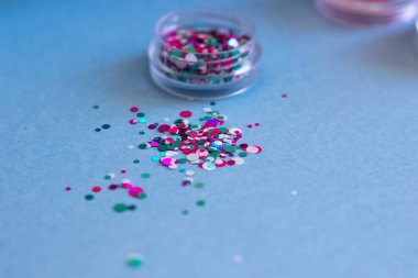 Mavi bir arka plan üzerinde dağınık tırnak tasarımı için glitter kavanoz.