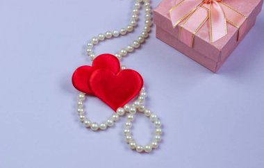 İnci ve Sevgililer mor bir arka plan üzerinde pembe bir kutu içinde bir hediye. Sevgililer günü ve Dünya Kadınlar günü