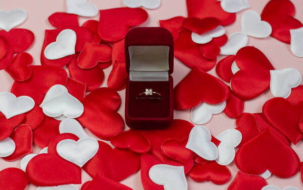 Кольцо в красной коробке на фоне червей красного и белого цвета. Обручальное кольцо в коробке. Концепция предложения о браке, День святого Валентина, Международный женский день
.