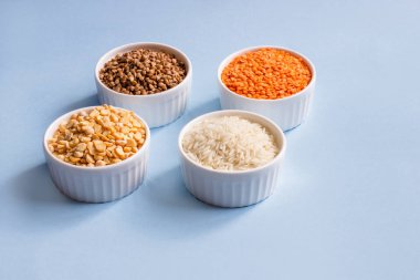Mavi arka planda çeşitli tahıl gevreği. Karabuğday, mercimek, pirinç, üst tabaklarda bezelye, yerin kopyası. Sağlıklı beslenme konsepti