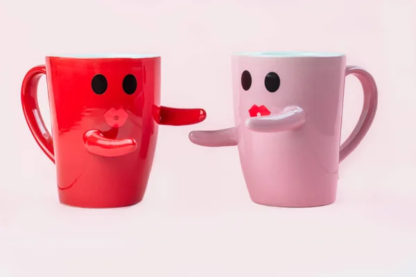 Friday\'s happy word. Two cups of coffee on a pink background with a smile face to the mug, hugging each other. The concept of love and relationships. Creative colorful greeting card
