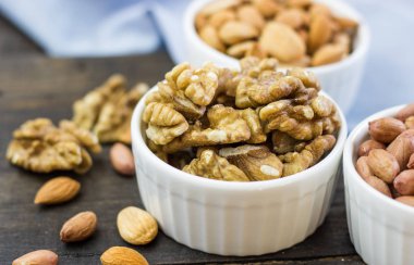 Ahşap bir masa üzerinde bir kase lezzetli fındık düzenleme. Sağlıklı yiyecek ve atıştırmalık, organik vejetaryen yiyecekler. Ceviz, badem, fıstık