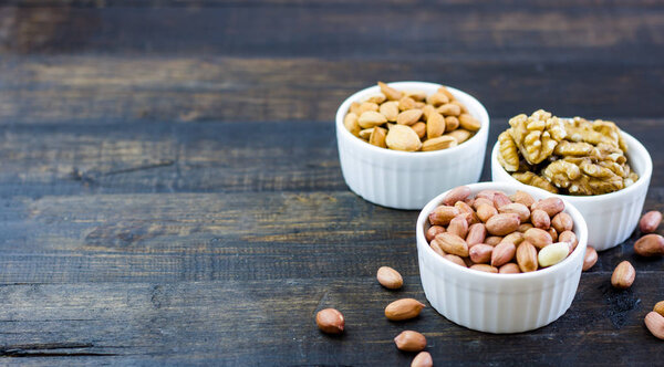 Tasty nuts arrangement in a bowl on a wooden table. Healthy food and snack, organic vegetarian food. Walnut, almond, peanut