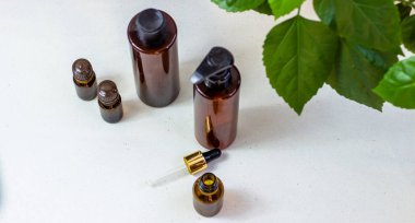 Koyu kozmetik şişeler ve açık bir arka plan üzerinde yeşil doğal yaprakları. Kopya alan Güzellik salonu blogger, salon terapi, minimalist kavram. Doğal çevre dostu kozmetik kavramı.