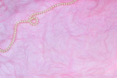 Pembe buruşuk kağıt doku arka plan üzerinde Inci kolye
