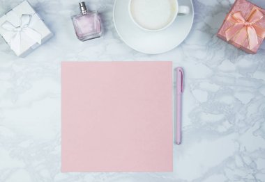 Beyaz mermer bir masada kadın aksesuarları. Pembe bir kağıt, pembe bir kalem masanın üzerinde bir bardak kahve ve diğer kadın kozmetik ürünleri. Pembe boş kart, yazmak için kağıt. İnscri eklemek için düzenName
