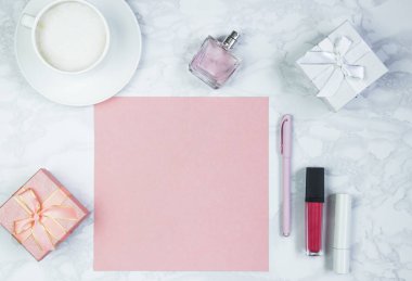 Beyaz mermer bir masada kadın aksesuarları. Pembe bir kağıt, pembe bir kalem masanın üzerinde bir bardak kahve ve diğer kadın kozmetik ürünleri. Pembe boş kart, yazmak için kağıt. İnscri eklemek için düzenName