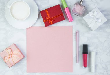 Beyaz mermer bir masada kadın aksesuarları. Pembe bir kağıt, pembe bir kalem masanın üzerinde bir bardak kahve ve diğer kadın kozmetik ürünleri. Pembe boş kart, yazmak için kağıt. İnscri eklemek için düzenName