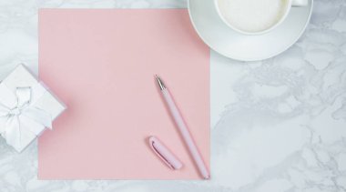 Pembe kağıt, pembe kalem, bir fincan kahve ve hediye kutuları masada. Pembe boş kart, yazı için sayfa. Yazıt eklemek için düzen. Üst görünüm, düz döşeme, kopyalama alanı
