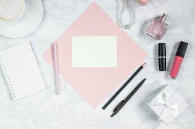 Beyaz mermer masaüzerinde kadın aksesuarları. Pembe bir kağıt, kalem, defter, parfüm, hediye kutusu, inci, bir bardak kahve ve diğer kadın kozmetikleri. Etiket eklemek için düzen. Düz döşeme, kopyalama alanı