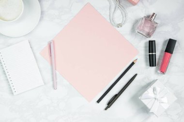 Beyaz mermer masaüzerinde kadın aksesuarları. Pembe bir kağıt, kalem, defter, parfüm, hediye kutusu, inci, bir bardak kahve ve diğer kadın kozmetikleri. Etiket eklemek için düzen. Düz döşeme, kopyalama alanı