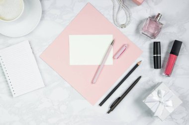 Beyaz mermer masaüzerinde kadın aksesuarları. Pembe bir kağıt, kalem, defter, parfüm, hediye kutusu, inci, bir bardak kahve ve diğer kadın kozmetikleri. Etiket eklemek için düzen. Düz döşeme, kopyalama alanı