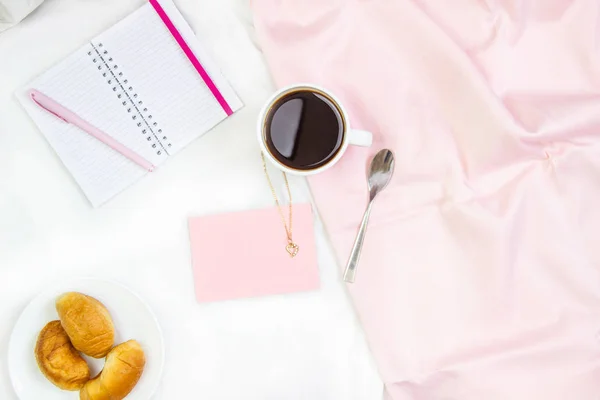 Frühstück im Bett. flache Komposition mit Kaffee, Croissants und einem Notizbuch zum Schreiben. Lifestyle Konzeptrahmen. Ansicht von oben auf Blättern — Stockfoto