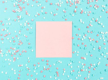 Kayıt düzeni. Yıldız ve yay ile dekoratif çok renkli elemanları ile mavi bir arka plan üzerine yazmak için pembe levha. Düz döşeme, üst görünüm.