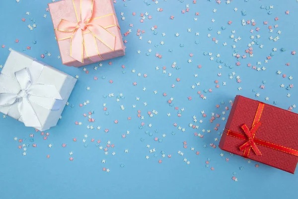 Geschenkschachteln auf blauem Hintergrund mit dekorativen mehrfarbigen Elementen mit Sternen und Schleifen. flache Lage, Draufsicht. — Stockfoto