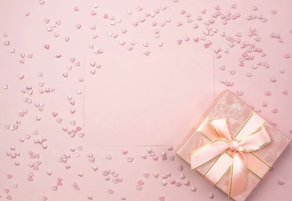 Pink sheet for writing and gift box on a pink background and decorative hearts. Marriage proposal concept, Valentines Day, International Womens Day. Flat lay, top view