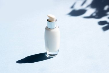 Yüz estetiği. Krema kavanozları, mavi arka planda yüz maskesi ve yaprakların sert gölgeleri. Güzellik blogcusu, prosedür salonu konsepti. Minimalizm.