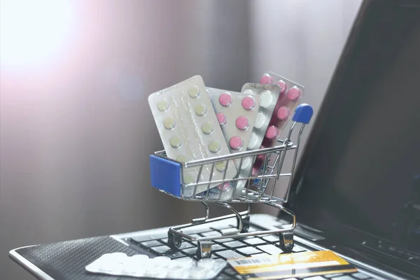 Online store with home delivery. Shopping basket with pills on laptop keyboard
