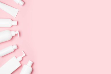 Pembe arka planda beyaz kozmetik kavanozlar. Cilt bakımı için makyaj malzemeleri