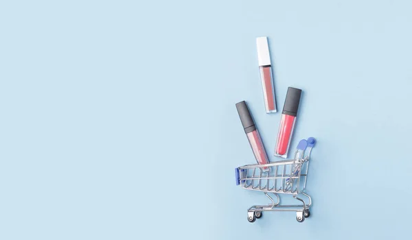 Kvinnors Läppstift Och Läppglans Shoppingvagn Med Blå Bakgrund Begreppet Att — Stockfoto