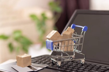 İnternetten alışveriş ve ev teslimatı. Alışveriş sepeti ve kutular dizüstü bilgisayarda..