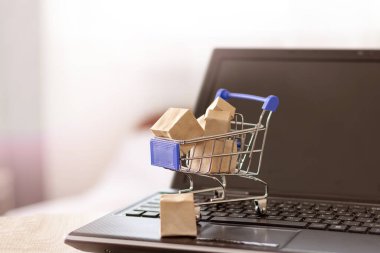 Alışveriş sepeti ve kutular dizüstü bilgisayar klavyesinde. Ev teslimatıyla çevrimiçi alışveriş
