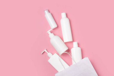 Pembe arka planda beyaz kozmetik kavanozlar. Cilt bakımı için makyaj malzemeleri.