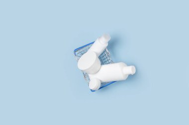 Beyaz kozmetik kavanozları bir alışveriş sepetinde yatıyor. İnternetten alışveriş. Dezenfeksiyon, çamaşır ve bakım ürünleri satın alınması.