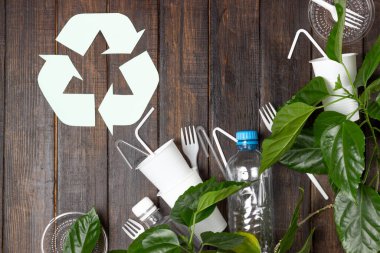 Plastik tabaklar, şişeler, bardaklar beyaz bir masada. Gezegen kirliliği