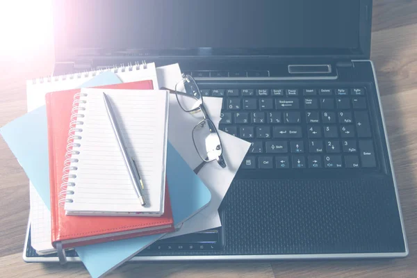 Workplace with laptop, notebook and glasses on a wooden table. Work from home. Blurred background.