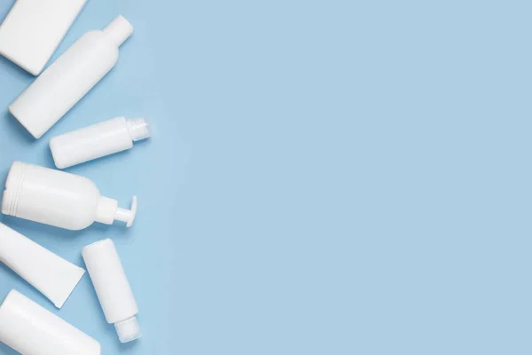 En uppsättning vita kosmetiska burkar för ansikte och kropp vård är i en korg på en blå bakgrund. Inköp av kosmetika och hygienprodukter, heminköp. — Stockfoto