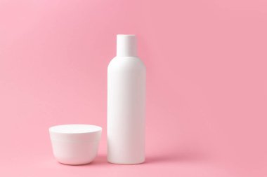Beyaz kozmetik şişeleri ve kavanozlar pembe arka planda metin eklenecek bir yerde.