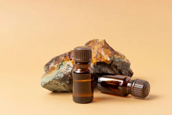 An amber bottle for essential oils and cosmetics stands next to the stone. Glass bottle. Dropper, spray bottle. Natural cosmetics concept.