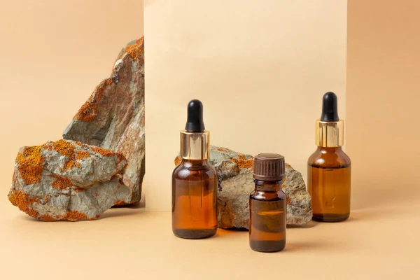 An amber bottle for essential oils and cosmetics stands next to the stone. Glass bottle. Dropper, spray bottle. Natural cosmetics concept.