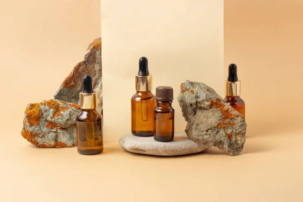 Naast de steen staat een amberkleurige fles voor essentiële oliën en cosmetica. Glazen fles. Druppelaar, spuitfles. Natuurlijke cosmetica concept. — Stockfoto