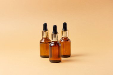 Gerekli yağlar ve kozmetik ürünleri için kehribar bir şişe taşın yanında duruyor. Pembe arka planda cam şişe. Damla, sprey şişesi. Doğal kozmetik konsepti.