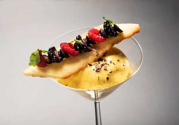美味的奶油甜点服务在一个优雅的锥形玻璃装饰与新鲜的覆盆子和黑莓的饼干顶部 — 图库照片