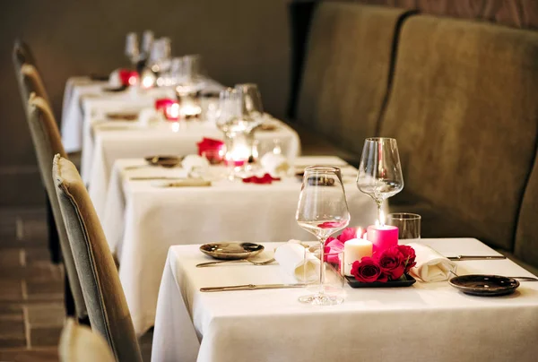 つの親密なディナーのキャンドルと赤いバラとエレガントなガラス製品を燃焼の Centrepieces とレストランでロマンチックなテーブルの設定 — ストック写真