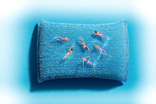 Grupo Pessoas Miniatura Nadando Uma Piscina Sobre Uma Almofada Azul — Fotografia de Stock