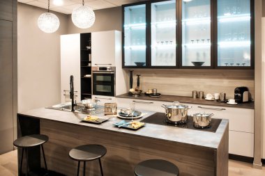 Tarafsız kahverengi modern mutfak iç ada bar tabureleri bir duvar boyunca büyük windows tarafından yaktı ve yerleşik hob ve lavabo ile donatılmış