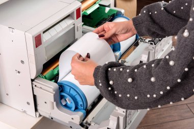Kadın bir rulo yeni fotoğraf kağıdı fotoğraf yazıcıda yazdırma ev veya ellerini görünümünü yakından studio ayarlama